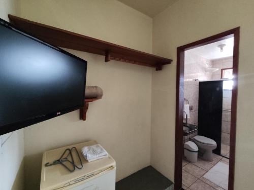a bathroom with a flat screen tv on the wall at Hotel Pousada Guayporã in Guarapari