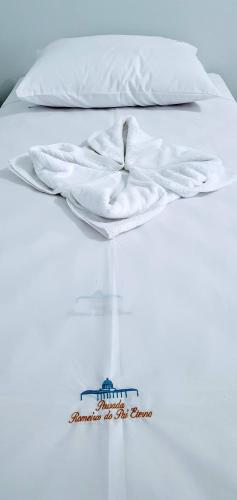 a white bed with a white blanket on top of it at Pousada Romeiros do Pai Eterno - Santuario Basilica de Trindade Goias in Trindade