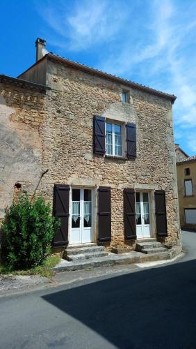 um edifício de tijolos com persianas pretas nas janelas em Grande maison de ville avec cheminée et loggia em Lacapelle-Biron