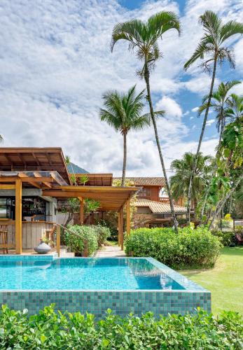 a swimming pool in front of a house with palm trees at Villa Sapê Pousada in Ubatuba