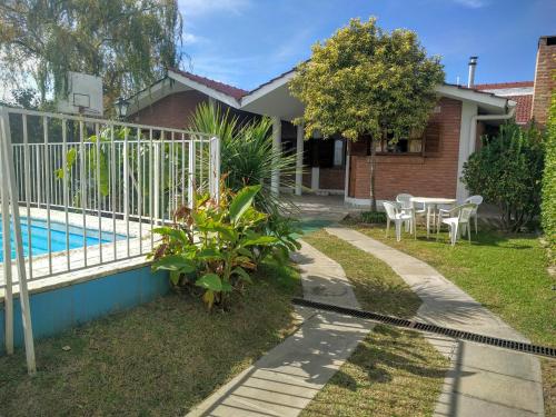 a house with a fence next to a swimming pool at Cabañas Bosque in Villa Carlos Paz