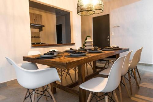 a dining room with a wooden table and white chairs at **Con Club de Playa y Alberca : Hasta 18 huéspedes** in Barra Vieja
