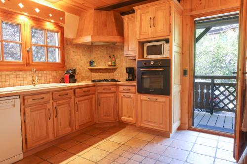 une cuisine avec des armoires en bois et un four à plaques de cuisson dans l'établissement Chalet Belle-Sofianna, à Saint-Gervais-les-Bains