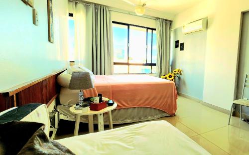 a hotel room with two beds and a table with a lamp at Farol Barra flat 412 in Salvador