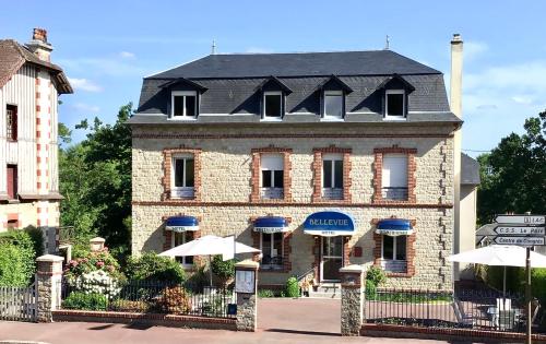een oud bakstenen gebouw met een zwart dak bij Hôtel Bellevue Bagnoles Normandie in Bagnoles de l'Orne