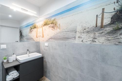 baño con lavabo y mural de la playa en Dziwnówek Apartament Horizon Park 4A, en Dziwnówek