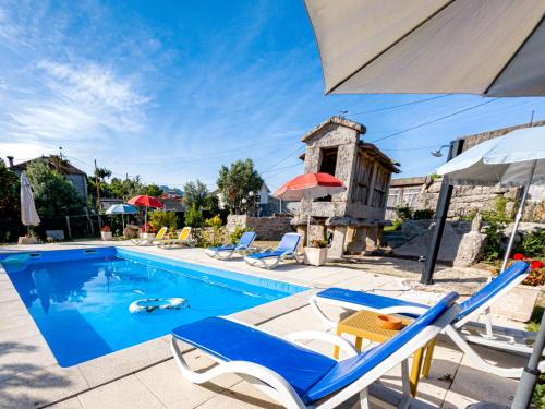 a pool with chairs and umbrellas next to a house at Alojamento de Crasto - Gerês in Geres