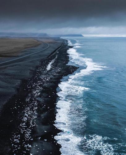 a black beach with the ocean and a cloudy sky at Keflavik Luxury apartment - KLA in Keflavík