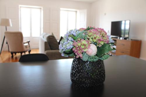 a vase filled with flowers sitting on a table at Alma Da Vila in Ponte de Lima