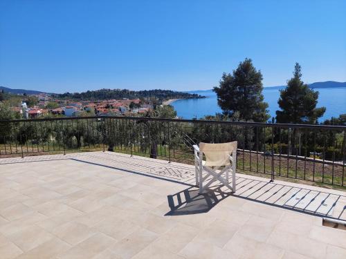 a chair sitting on a patio overlooking the water at Villa Johell in Neos Marmaras