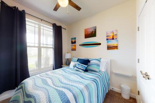a bedroom with a bed with blue pillows and a window at Millville by the Sea- 23923 Pembroke Lane in Millville