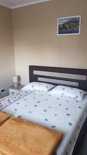 een slaapkamer met een bed met een wit dekbed bij Apartment Lidija in Herceg-Novi