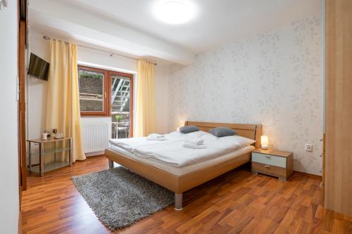 a bedroom with a white bed and a window at Penzion Balcony in Český Krumlov