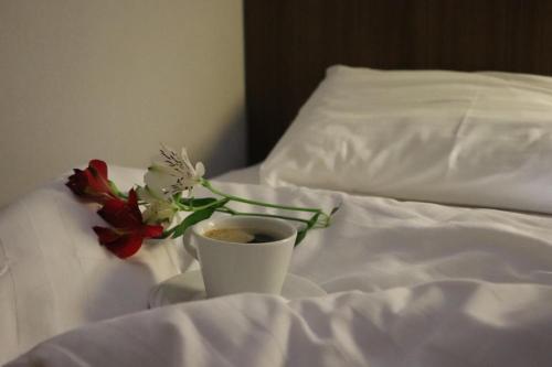 a cup of coffee and a bouquet of flowers on a bed at Martvili Palace in Martvili
