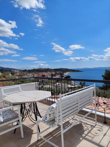 a table and chairs on a balcony with a view of the water at Villa Johell in Neos Marmaras