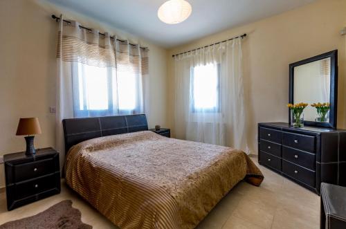 a bedroom with a bed and a dresser and a mirror at SunShine Villa Paphos in Nicosia