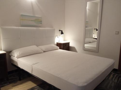 un letto bianco in una stanza con specchio di Voramar debaix a Alcudia