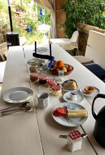 a white table with plates of food on it at Guest Room Agro-turismo Quinta da Fonte Bed&Breakfast in Figueiró dos Vinhos