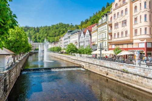 a river in a city with buildings and a fountain at Apartmán Ondřejská 2159 Karlovy Vary in Karlovy Vary