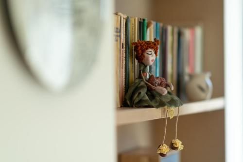 un estante de libros con una muñeca sentada en él en Poilsis klonyje, en Druskininkai