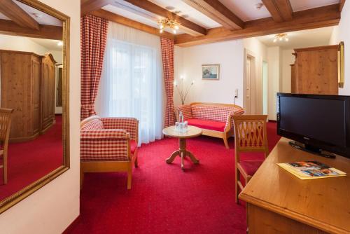 a living room with a television and a table and chairs at Sporthotel Cristall in Fulpmes