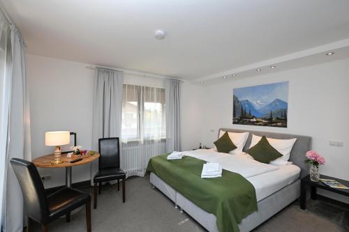 a bedroom with a bed and a table and a desk at Hardi's Hotel in Inzell