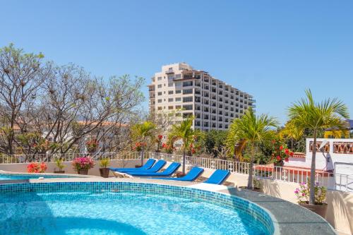 una piscina en un hotel con sillas azules y un edificio alto en Suites Plaza del Rio - Family Hotel Malecón Centro, en Puerto Vallarta