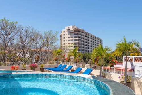 een zwembad in een hotel met blauwe stoelen en een hoog gebouw bij Suites Plaza del Rio - Family Hotel Malecón Centro in Puerto Vallarta