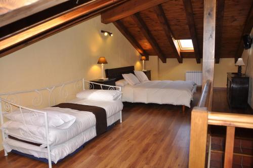 Duas camas num quarto com pisos em madeira em El Rincón de la Trilla - El Linar em Horcajo de la Sierra