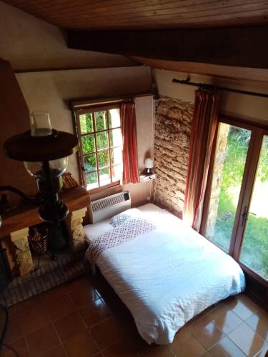 une chambre avec un lit dans une pièce avec des fenêtres dans l'établissement Grande maison de vacances au calme, à Lentignac
