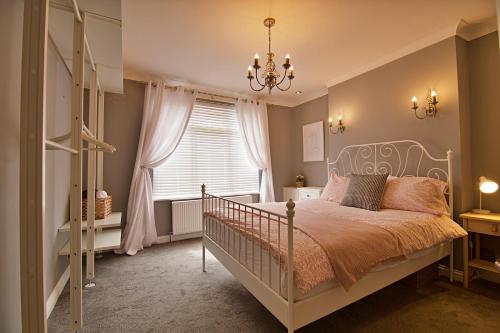 a bedroom with a bed with a chandelier and a window at 'Bayview' at stayBOOM in Morecambe