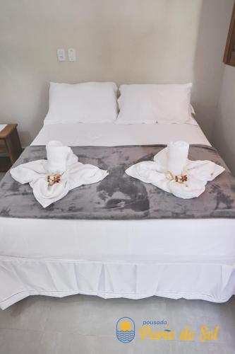 a white bed with two white towels on it at Pousada Porto do Sol in Nova Viçosa