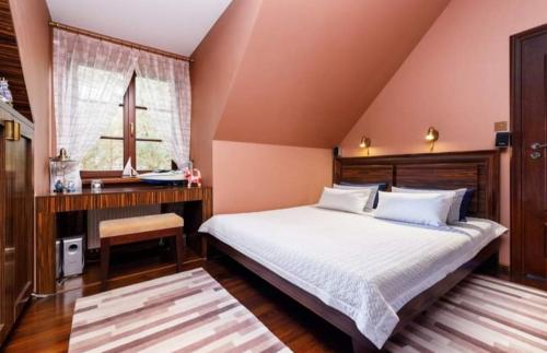 a bedroom with a bed and a desk and a window at WILLA NAD STAWEM MAZURY in Piecki