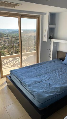 a bed in a room with a large window at La Villa Toscana: Pool & Elah Valley vineyard view in Adderet