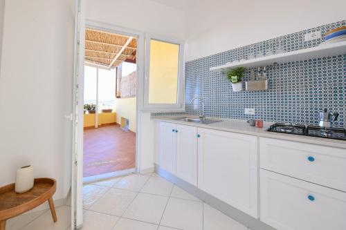 a kitchen with white cabinets and blue tiles on the wall at La Dimora Dei Nonni in Ischia