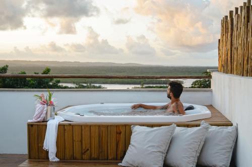 Ein Mann in einer Whirlpool-Badewanne auf einem Balkon in der Unterkunft Nomads Flats in Itacaré