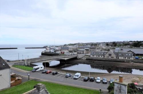 a city with cars parked on a road near the water at Caithness Inn in Wick