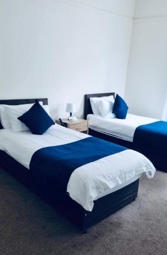 two beds in a room with blue and white at Caithness Inn in Wick