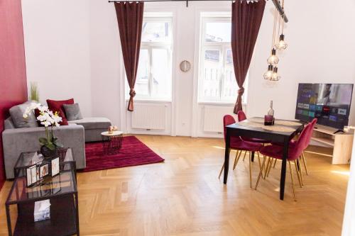 ein Wohnzimmer mit einem Tisch und einem Sofa in der Unterkunft Schönbrunn Serenity Luxurious Ruby Apartment with Palace Views in Wien