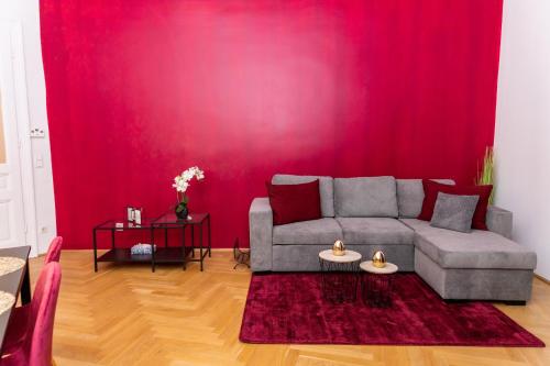 ein Wohnzimmer mit einem Sofa und einer roten Wand in der Unterkunft Schönbrunn Serenity Luxurious Ruby Apartment with Palace Views in Wien