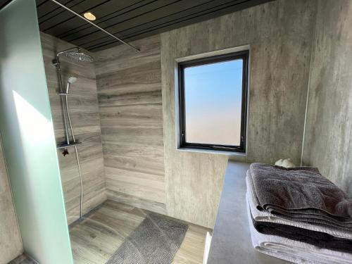 ein Bad mit einer Dusche und einem Fenster in der Unterkunft Dalsmynni in Blaskogabyggo