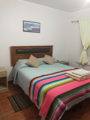 Un dormitorio con una cama con una manta de colores. en Alto Noa San Pedro de Atacama en San Pedro de Atacama