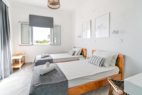 two beds in a room with white walls and windows at Andrikas Villa at Xenios Avlais in Zakynthos Town