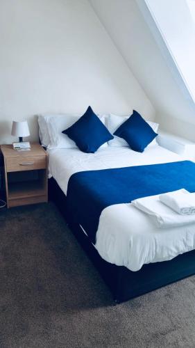 a bedroom with two beds with blue pillows and a table at Caithness Inn in Wick