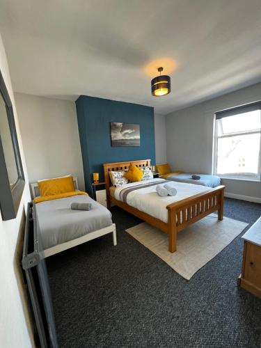 a bedroom with two beds and a blue wall at PolkaDot Winter Gardens - 2 x Large Modern Apartments, Central Blackpool in Blackpool