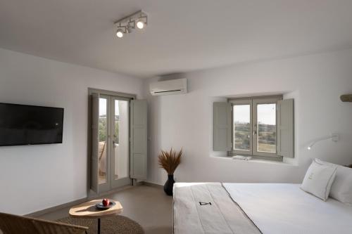 a white bedroom with a bed and a tv at Ikies of Mykonos in Mýkonos City