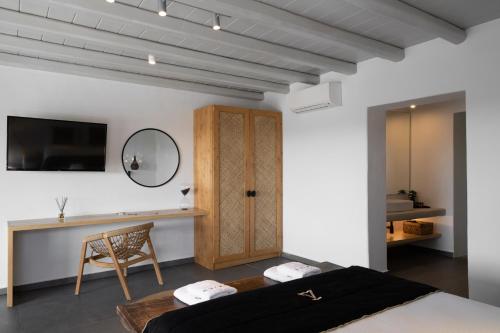 a bedroom with a bed and a desk and a television at Ikies of Mykonos in Mýkonos City