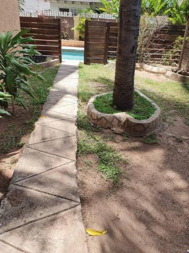 a sidewalk next to a tree next to a pool at Central Upscale New Kingston Apt with pool in Kingston