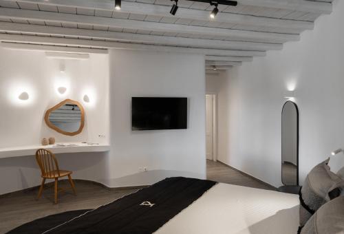 a bedroom with a bed and a tv on a wall at Ikies of Mykonos in Mýkonos City