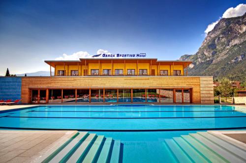 un hotel con piscina di fronte a un edificio di Garda Sporting Club Hotel a Riva del Garda